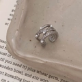Macro-opname van zilveren meerlaagse oormanchet met parels en zirkoon op keramische plaat - Zilveren meerlaagse zirconia parel ear cuff / Zilver