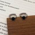 Détail de créoles en argent avec un zircon noir serti à quatre griffes sur fond de livre - Boucles d'oreilles en argent avec zircon noir