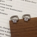 Gros plan sur des créoles argentées avec zircone cubique ronde sertie à quatre griffes - Boucles d'oreilles en argent avec zircon blanc