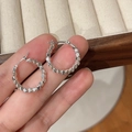 Close-up of silver geometric hoop earrings with textured beads on a velvet tray - Silver Small Square