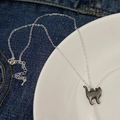 Sleek silver necklace featuring a dark mother of pearl cat pendant on denim and white plate - Black Cat / Black