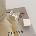 Détail macro de boucles d'oreilles cubes avec finition dorée brossée sur fond minimal - Boucles d'oreilles brossées carrées géométriques argentées