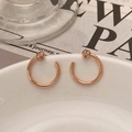 Detail von Roségold-C-Ohrringen mit pavé-gefassten Diamantkugeln auf einer weißen Schale - C-Form Ohrstecker / Roségold