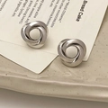 Macro detail van zilveren gevlochten meerlaagse oorringen op een keramische schaal - Zilver