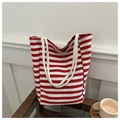 Vista dettagliata di una borsa in tela a righe rosse e bianche su un tavolo in legno - A righe rosse e bianche / Rosso