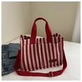 Detalle del bolso tote de lona a rayas rojas y blancas con correa de hombro y etiqueta de cuero - Rojo