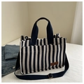 Detalle del bolso tote de lona a rayas con bolsillos frontales y etiqueta de cuero - Negro