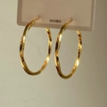 Primer plano de aros dorados retorcidos con agujas de plata S925 en tarjeta de venta - 4cm / Dorado
