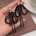 Handmade black beaded bow earrings with heart stud and tassel drops shown in hand - Silver Tassel Earrings (Black Beads)