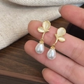 Detail of gold butterfly earrings with cat eye stones and teardrop pearl charms - Gold