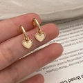 Gros plan détaillé des boucles d'oreilles cœur doré avec bords perlés milgrain élégants - Boucles d'Oreilles Coeur Or Poli