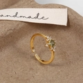 Detailed macro view of an emerald green zircon ring with gold plating on handmade paper - Gold Green Zirconia Ring