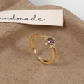 Macro shot of gold adjustable starburst ring with round purple gemstone and white zircons - Gold Purple Zirconia Ring