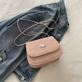 Roze trendy kettingtas met zilveren vlinder op een denim achtergrond - Roze