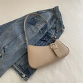 Bolso baguette beige minimalista con hebilla plateada sobre fondo denim azul - Caqui