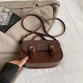 Borsa a sella marrone in pelle con doppia fibbia e logo moda su sfondo di un blazer - Marrone