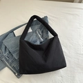 Bolso tote grande de nailon negro acolchado sobre vaqueros azules estilo urbano casual - Negro