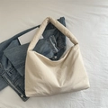 Bolso tote de nailon acolchado en beige con correa ancha sobre chaqueta vaquera - Blanco