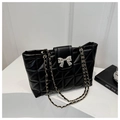 Detalle de bolso tote acolchado negro con cierre de lazo plateado y asa de cadena - Negro