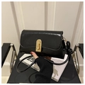Detalle de bolso en piel negra brillante con cierre dorado y elegante correa con nudo - Negro
