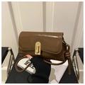 Detalle de bolso baguette marrón vintage con cierre dorado y correa con nudos - café