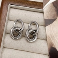 Makroaufnahme von silbernen Knoten-Ohrringen mit mehrlagigen Ringen auf einem Display - Creolen / Silber