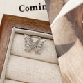 Dettaglio macro di un anello a farfalla in argento con zirconi in una scatola di legno fine - Polsino per orecchio a farfalla / Argento