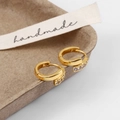 Details von goldenen Huggie-Ohrringen mit Zirkonia auf einem handgefertigten Tablett - Mikro-eingelegte Kleine Creolen / Gold