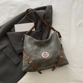 Dark grey hobo bag with brown leather strap and metallic M logo on a grey blazer - Gray