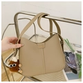 Detail view of khaki leather bag with FASHION buckle and plush charm on a rack - Glasses Pom-Pom Pendant / Khaki