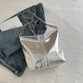 Metallic silver tote bag with mirror finish and chain strap on denim jacket background - Silver