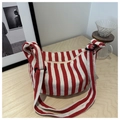 Detail of red and white striped canvas tote with zipper closure and adjustable strap - Red