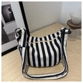 Detailed shot of striped canvas handbag with thick adjustable strap on wooden table - Blue