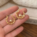 Detalle de pendientes trenzados dorados con perla sobre un fondo de tonos cálidos - Estilo de Perla Única con Textura Tejida (A-1266) / Dorado