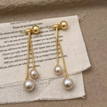 Detail shot of champagne pearl tassel earrings on a textured stone and fabric background - Champagne Pearl Tassel Stud Earrings