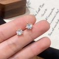 Macro shot of a pair of gold four-prong round-cut cubic zirconia studs held by hand - Gold