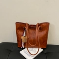 Sac cabas en cuir marron vintage avec pendentif ours en peluche sur un banc sombre - Avec Pendentif / Marron