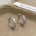Close-up of silver zircon hoop earrings on a textured handmade display tray - Silver Zirconia Earring Hoops