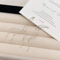 Dettaglio ravvicinato di orecchini a onde argentate con texture liscia e intrecciata - Linea per Orecchio con Nappa a Onda Argento