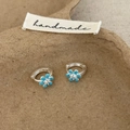 Details von silbernen Creolen mit himmelblauen Emaille-Blumen und Zirkonia-Mitte - Blaue Blumenohrringe