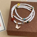 Detail of layered beaded bracelet featuring shell butterfly pendant and colorful charms - Handmade Beaded Style