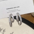 Détail macro de boucles d'oreilles doubles cercles argentés avec zircons baguette sertis - Boucle d'oreille argentée à double boucle entrelacée / Argenté