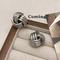Detailansicht der silbernen Knoten-Ohrstecker auf einem beigen Samt-Schmuckhalter - Silber