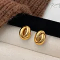 Minimalistische goldene geometrische Dreh-Ohrringe mit Hochglanzfinish auf herbstlichem Grund - Gold