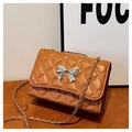 Detail of brown quilted shoulder bag with silver bow buckle and woven metal chain strap - Brown