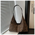 Detailed close-up of leopard print hobo bag with black leather strap on a textured background - Coffee
