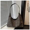 Detailed view of leopard print texture and black leather strap on a large hobo bag - Tan