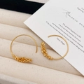 Elegant gold plated hoop earrings featuring wheat ear patterns on a soft velvet cushion - Gold