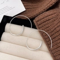 Macro detail of silver spiral earrings on beige velvet tray with autumn knit decor - Silver