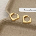 Macro shot of minimalist gold geometric square earrings resting on a natural pulp tray - Gold